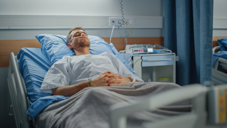 Hospital Ward: Portrait of Handsome Young Man Wearing Nasal Cannula Sleeping in Bed, Fully Recovering after Sickness. Male Patient Dreaming About Hisの写真素材