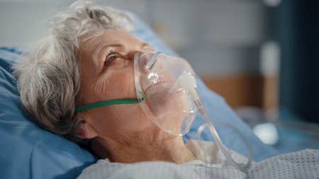 Hospital Ward: Portrait of Beautiful Elderly Woman Wearing Oxygen Mask Sleeping in Bed, Fully Recovering after Sickness. Old Lady Dreaming of Herの写真素材