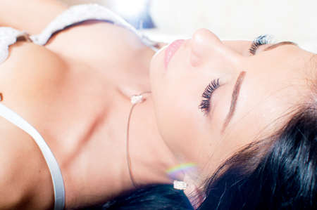 having spa happy relaxing lying in bed eyes closed one super sexy luxury glamor girl elegant pretty lady in great shape with long hair posing on light copy space background portrait picture closeupの写真素材
