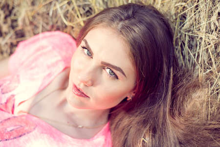 closeup portrait of beautiful young woman having fun relaxing lying on hay happy and looking at camera の写真素材