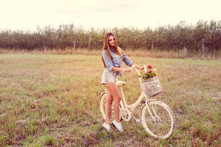 happy cycling time: portrait of beautiful brunette young woman having fun with bicycle on green summer outdoors copy space backgroundの写真素材