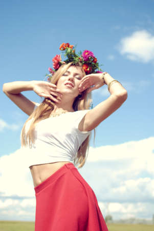 summer beauty joy: portrait of beautiful blonde young woman wearing flower crown having fun relaxing enjoying eyes closed on green outdoors copy space backgroundの写真素材