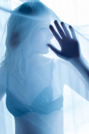 close up portrait of blond happy pretty lady having fun hiding in lingerie or bikini & relaxing looking on window light copy space backgroundの写真素材