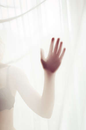 close up on hand of sexy pretty lady having fun hiding in lingerie or bikini on window light copy space backgroundの写真素材