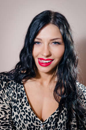 closeup portrait of showing tongue beautiful sexy young lady with blue eyes having fun sensually looking at camera on light copy space backgroundの写真素材