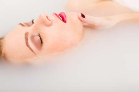 sleeping beauty in spa: closeup portrait of sexy elegant pinup girl with silk skin having fun happy relaxing lying in milk water on copy space backgroundの写真素材