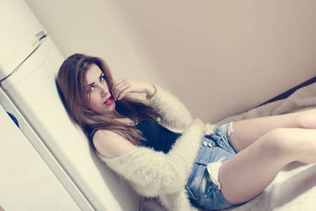 hungry & diet: portrait of beautiful young lady sitting relaxing near fridge on the kitchen floor and copy space backgroundの写真素材