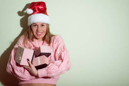 portrait of Santa Girl in Christmas hat with gifts boxes on light green copy space backgroundの写真素材