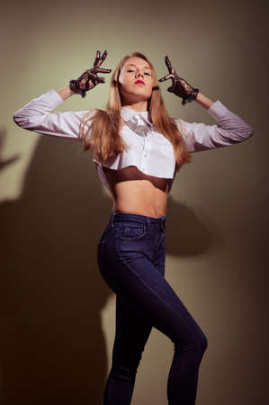 Blonde in black transparent gloves, shirt and jeans posingの写真素材