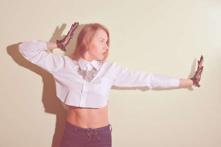 Blonde stylish girl in black transparent gloves posing in jeansの写真素材