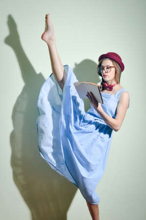 pretty ballet dancer in a red hat and glasses reading a bookの写真素材