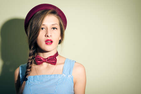 pretty girl in red hat and bow tie looks surprisedの写真素材