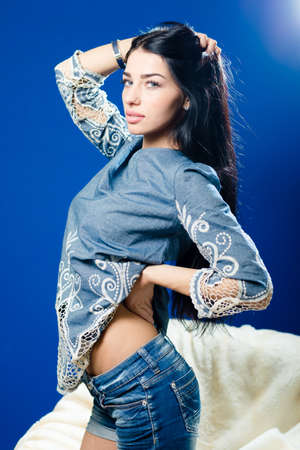 Portrait of beautiful young woman posing on blue light copy space background