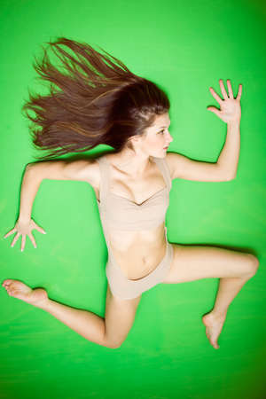 Image of beautiful sexy female with perfect fit body in running shape on green copy space backgroundの写真素材