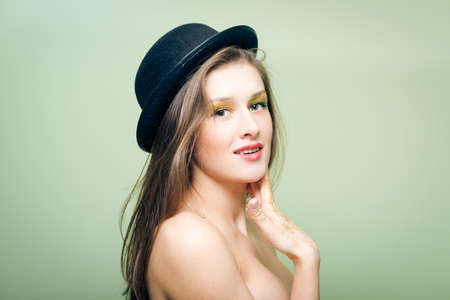 Closeup portrait of covered in shining make up sexy beautiful young woman in bowler hatの写真素材