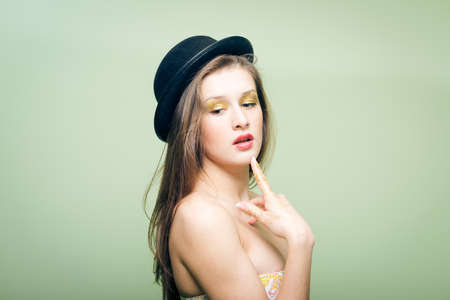 Closeup portrait of covered in shining make up sexy beautiful young woman in bowler hatの写真素材