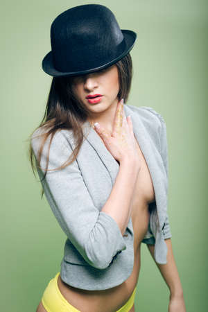 Portrait of romantic sexy beautiful young lady in bowler hat and yellow underwear with bare breasts and stomach on copy space backgroundの写真素材
