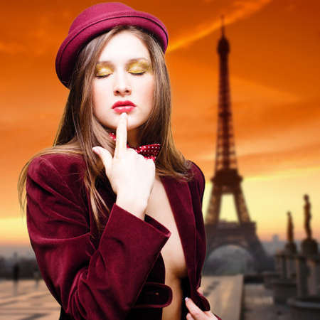 Portrait of romantic sexy beautiful young lady topless in elegant coat and red hat on Eiffel Tower copy space backgroundの写真素材