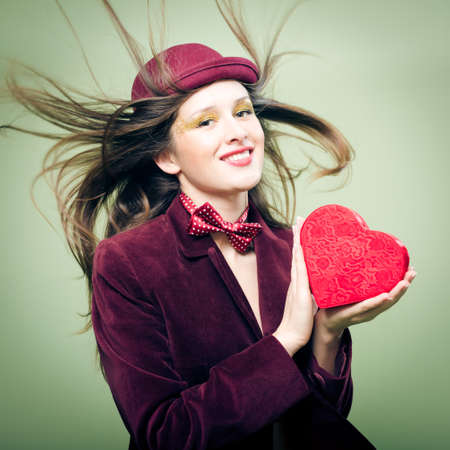 Portrait of romantic sexy beautiful young lady with red present box in the form of heartの写真素材