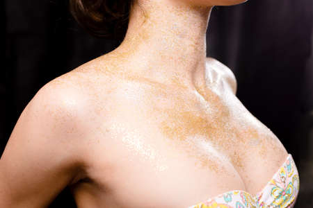 Shining makeup on beautiful topless young lady sensually hiding breasts on black background, close up pictureの写真素材