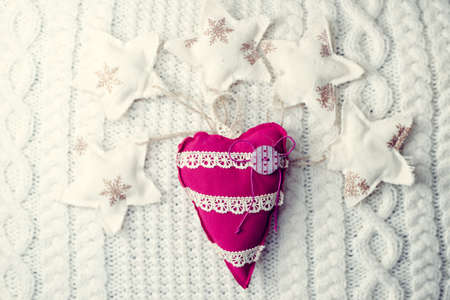 Close up image of handmade red heart on knitted background surrounded with decorative starsの写真素材