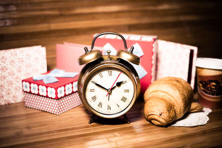 Image close up on set of alarm clock gift boxes and croissant with hot drinkの写真素材
