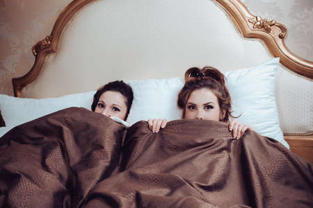 Portrait of sexy beautiful young ladies in bed and looking at cameraの写真素材