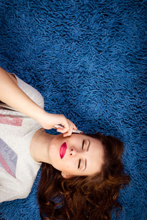 Picture of sexy young beautiful woman relaxing over blue copy space and talking on mobile phoneの写真素材