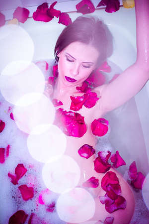 Portrait of elegant sexy beautiful girl with silk skin having fun laying in water bath & looking at...