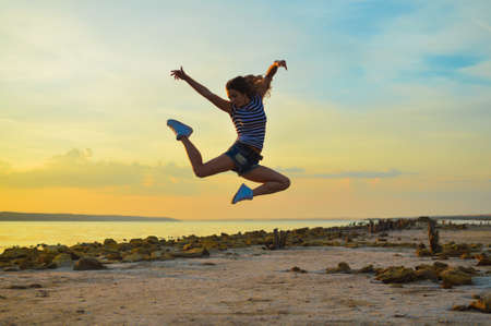 Sexi young jumping up high  in mid air on beach at sunriseの写真素材