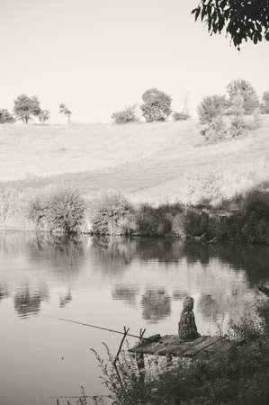 Black and white photography of kid fishing in the water on outdoors copy space backgroundの写真素材