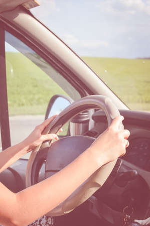 Two hands holding steering wheel inside car with blurred roadの写真素材