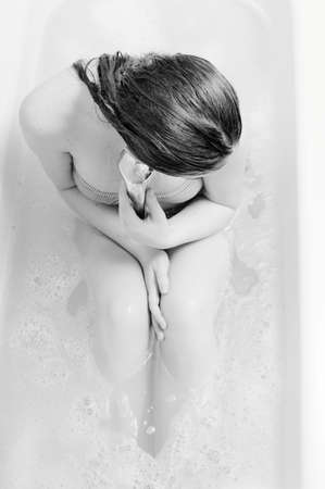 Picture of beautiful young lady having fun relaxing in bath holding shower on soap water copy space background. Black and white imageの写真素材