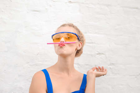 Portrait of funny girl balancing with pencil on lips. Young woman wearing big protecting glasses on...