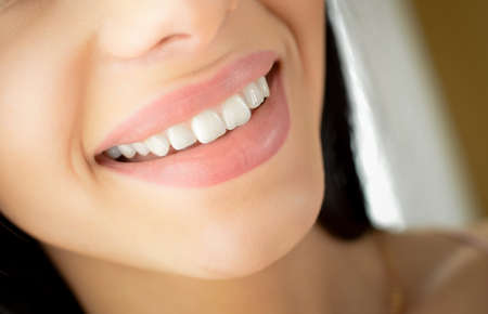 Picture of beautiful happy smile. Closeup of white teeth and natural lips on blurred indoor background.の写真素材