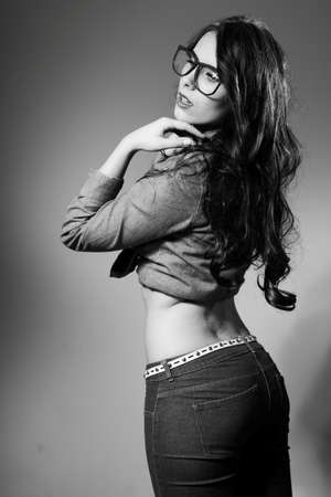 Black and white photography of young pretty lady wearing jeans long sleeve short and trousers. Girl looking at camera through hipster glasses.の写真素材