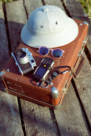 Travel background with pith helmet, camera, sunglasses and cellphone on top of retro suitcase. Exploration conceptの写真素材