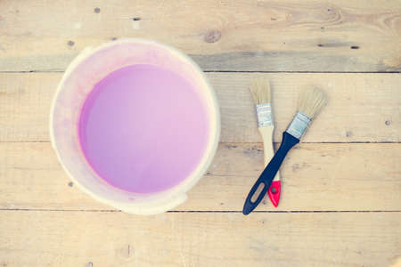 Color bowl with pink paint on wood board and two brushes as concept of  decorの写真素材