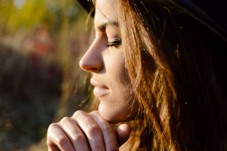 Portrait of beautiful young lady sunning in autumn. Sideview of pretty girl with closed eyes on golden fall outdoor background.の写真素材