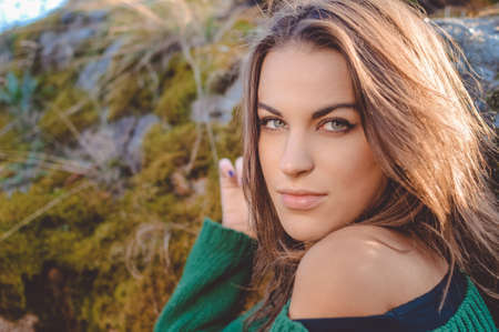 Portrait of sexy beautiful young lady in green sweater looking at camera. Pretty girl with naked...
