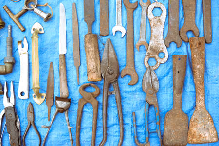 Picture of different metal aged tools. Different scissors and rusty secateurs on blue indoor...