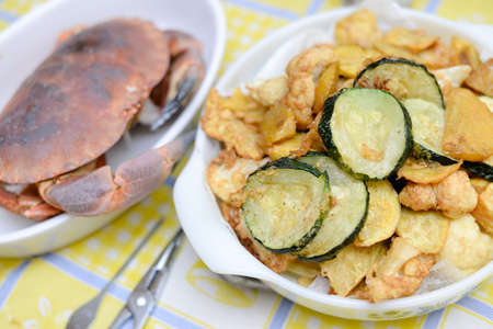 Picture of white dishes with crab and fried vegetables. Tasty dinner on plated tablecloth indoor background.の写真素材