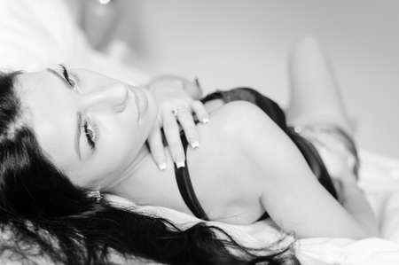 Portrait of one sexy luxury pretty lady in great shape with long hair having fun happy relaxing laying in bed on light background. Black and white photographyの写真素材