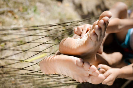 Picture of man and little child's feet resting in hammock. Closeup of happy family tickling and having fun on sunny summer day background.の写真素材