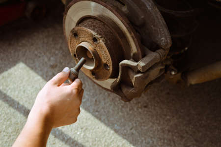 Picture of man changing old wheel. Closeup of hand working with disk and brake block on blurred background.の写真素材