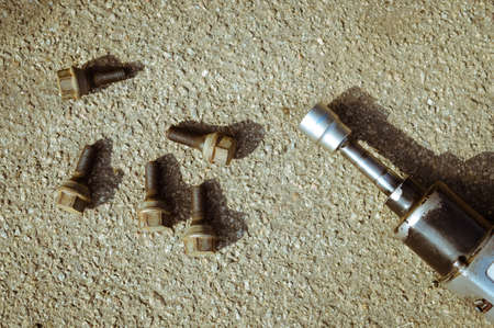 Picture of five aged rusty bolts and pneumatic screw driver. Set of old hand tools on asphalt...
