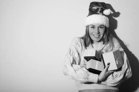 Portrait of exciting pretty girl in Santa hat with gifts. Black and white photographyの写真素材