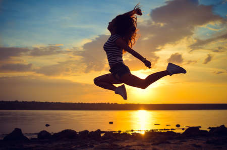 Picture of beautiful young amazed lady having fun jumping high over open water on summer outdoors copy space backgroundの写真素材