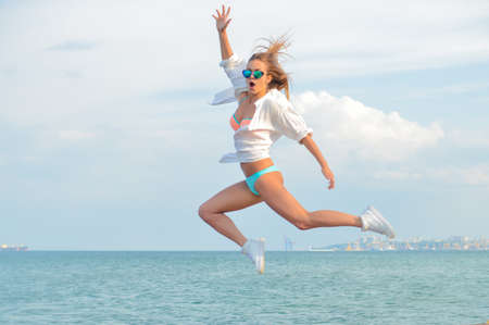 Picture of amazed beautiful young woman having fun in high jump over outdoors copy space backgroundの写真素材