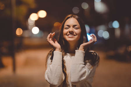 Portrait of young beautiful female smiling in joy and expressing sincere delight with charming outdoor evening backgroundの写真素材